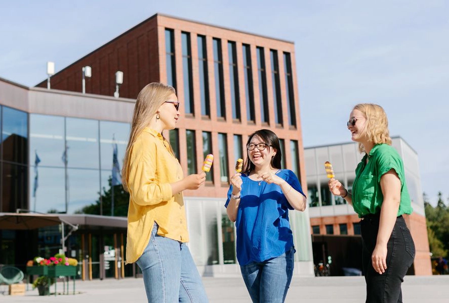 Three women are chatting outdoors with ice creams in their hands. - Aalto Yliopisto / Petri Anttila