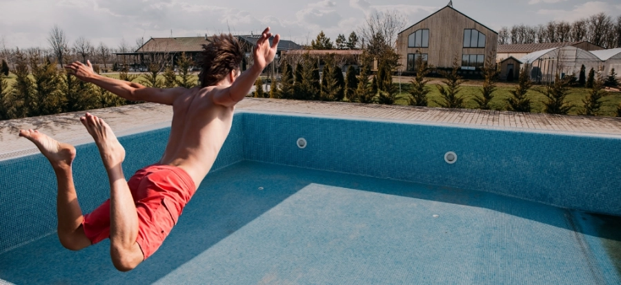 A man jumps into an empty swimming pool. A man jumps into an empty swimming pool.