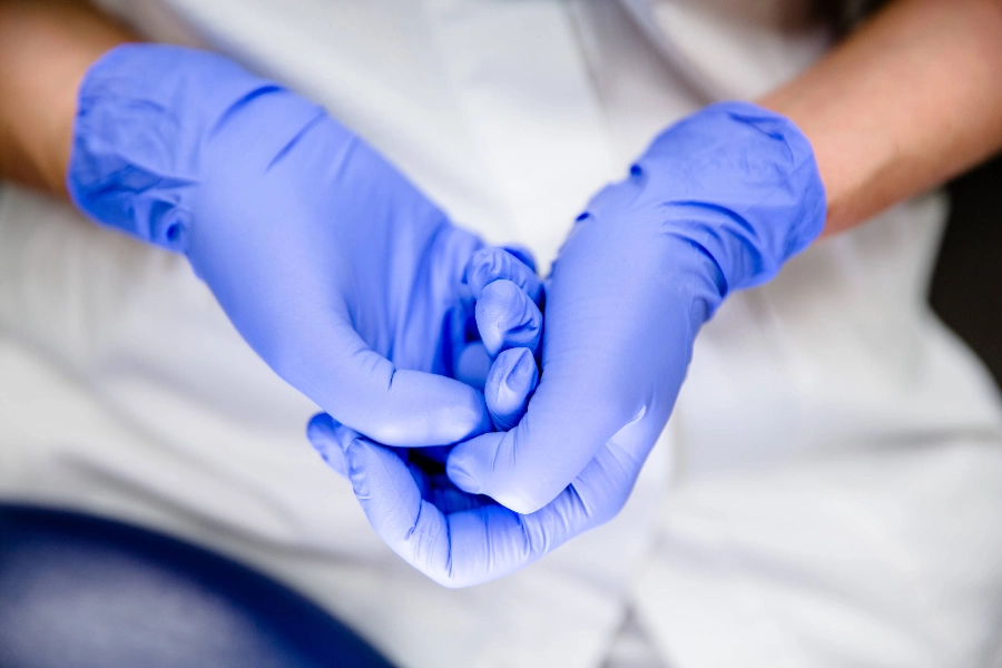 Hands protected by rubber gloves resting on top of each other